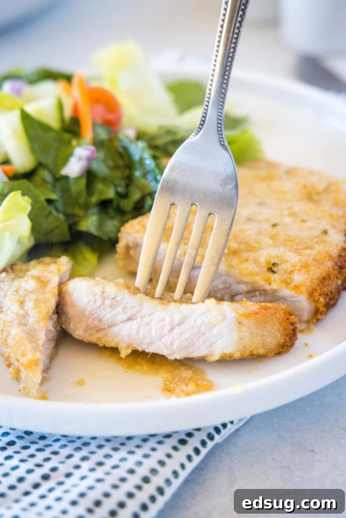 Perfectly sliced air fryer boneless pork chop served on a plate with a fork.