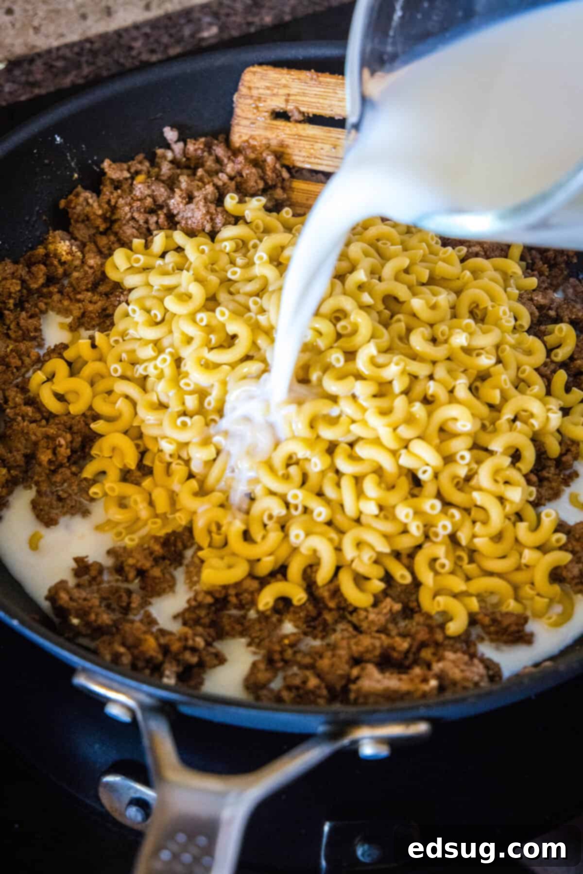 Homestyle Cheeseburger Macaroni 4 Cooked ground beef in a skillet with uncooked elbow macaroni, milk, and water being stirred together