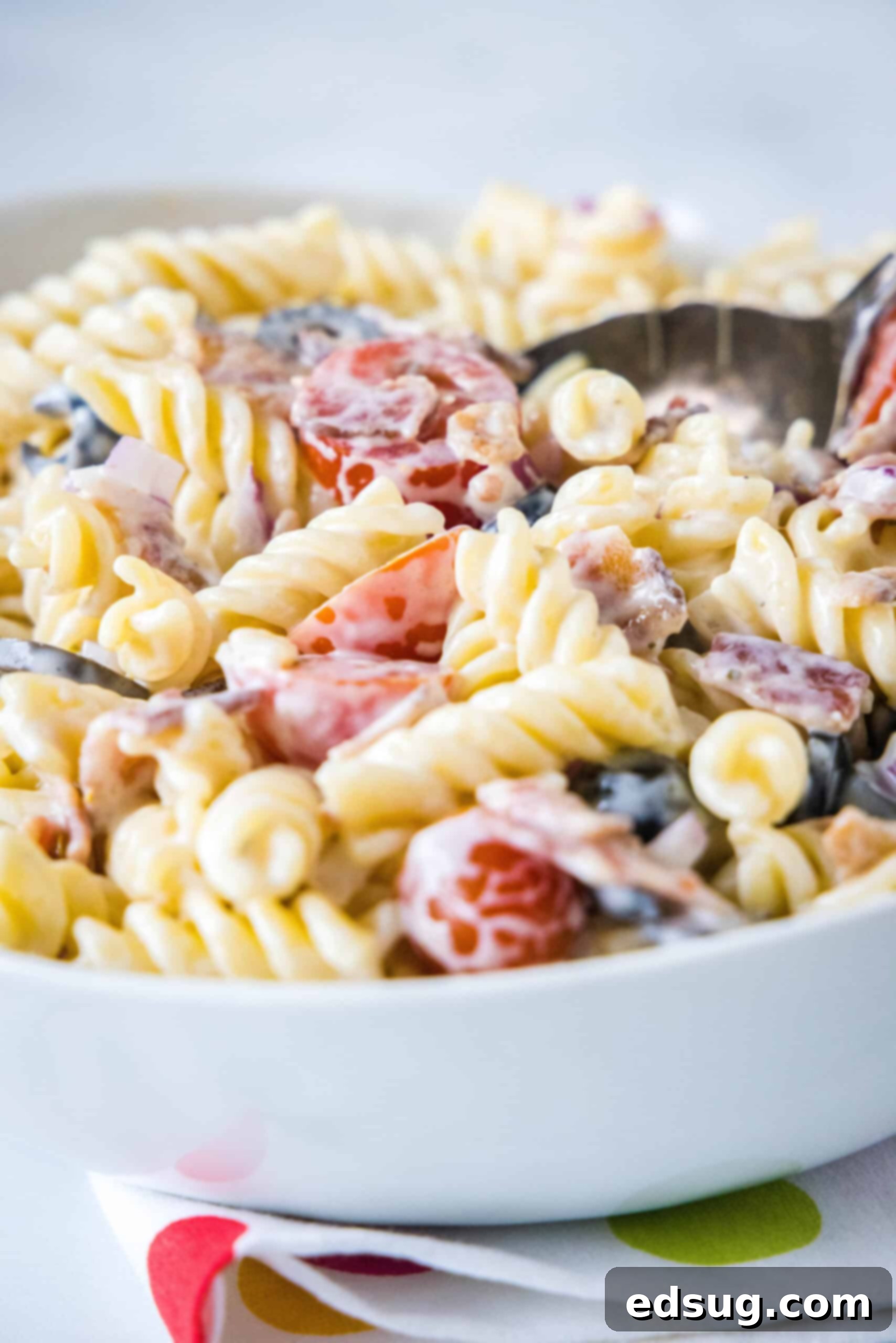 A vibrant bowl of ranch pasta salad, showcasing the creamy dressing, colorful vegetables, and crispy bacon, ready to be served.