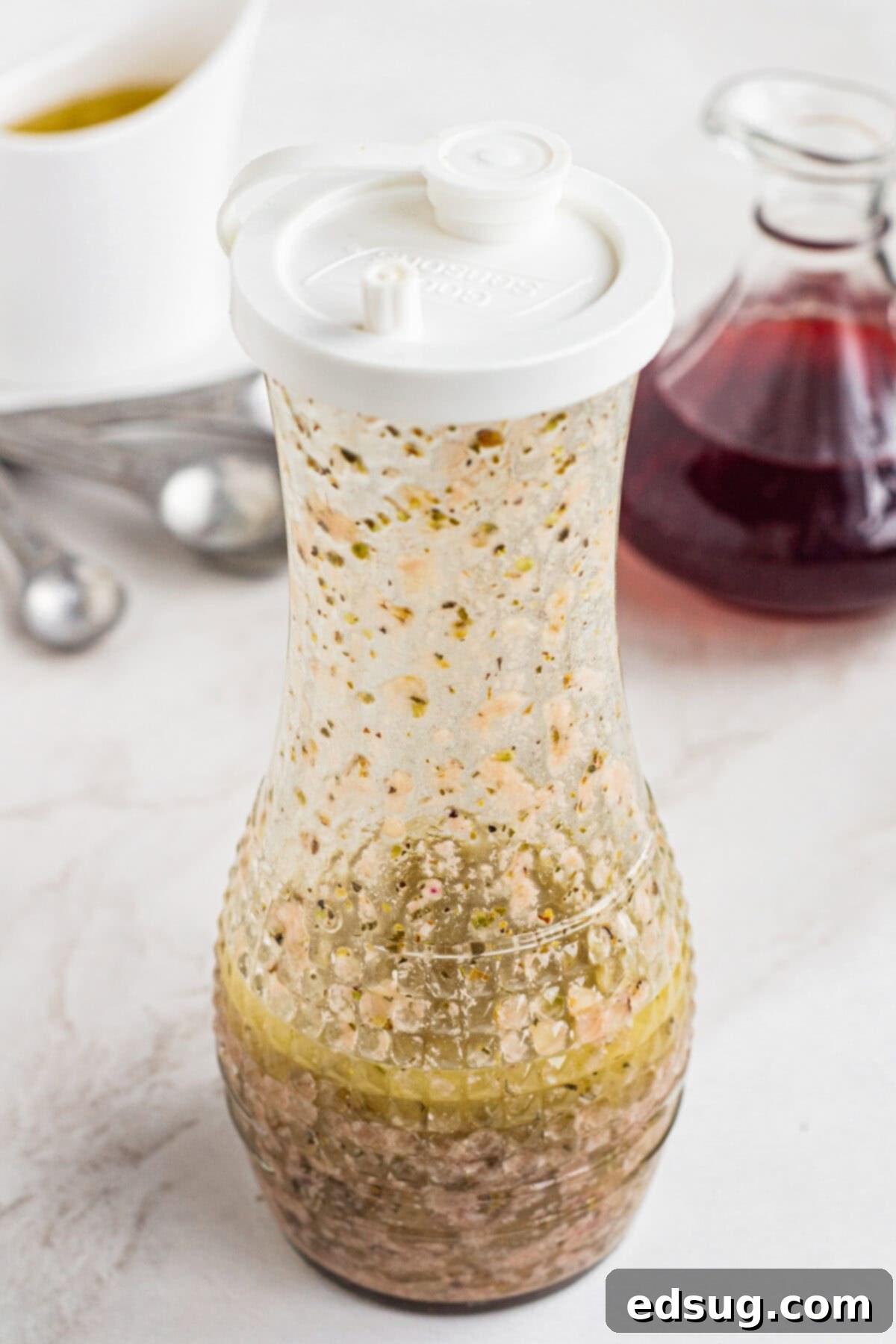 Emulsified red wine vinaigrette inside a glass carafe after shaking, showing a smooth, cohesive dressing.