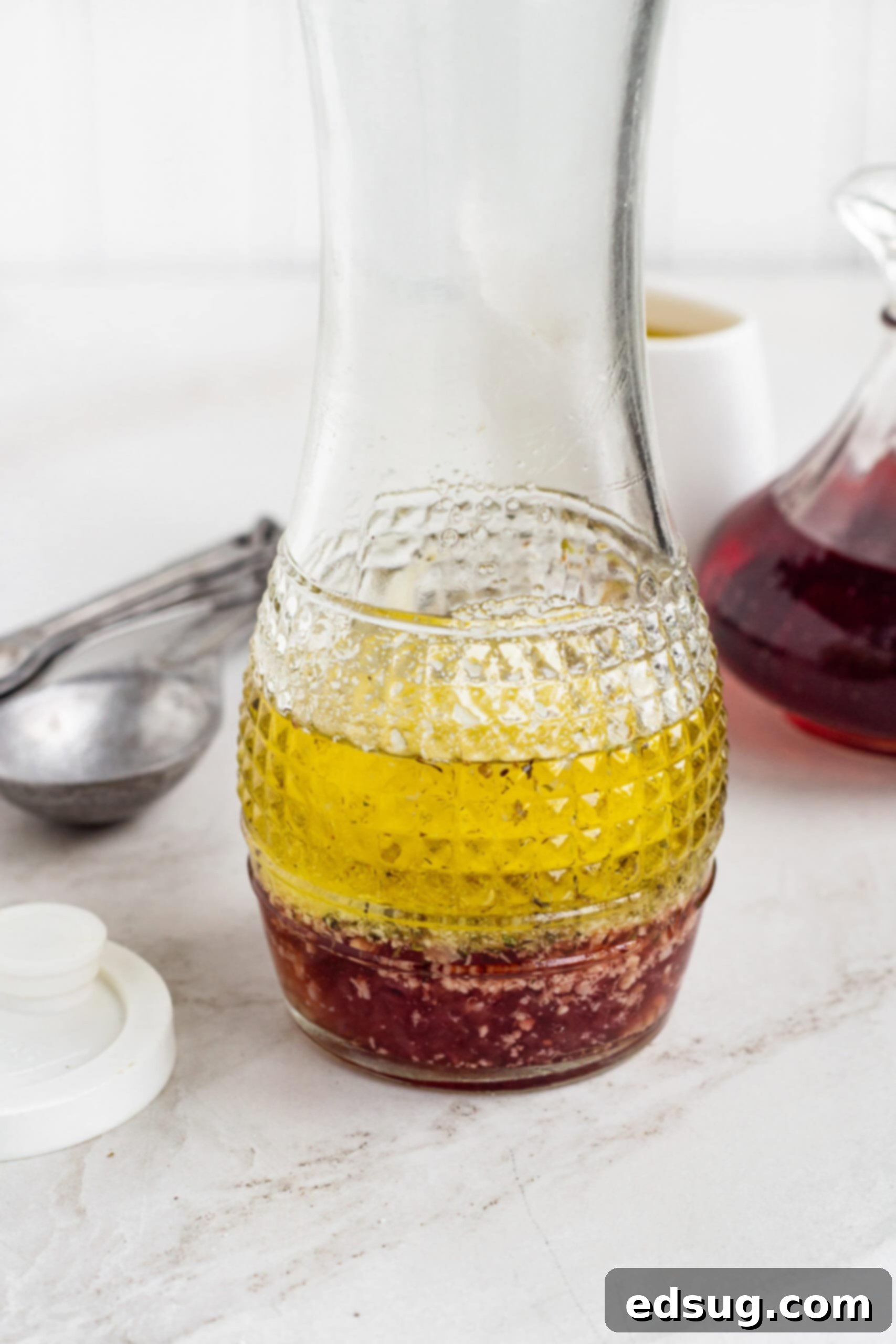 A glass carafe filled with perfectly emulsified red wine vinaigrette, ready to be served.