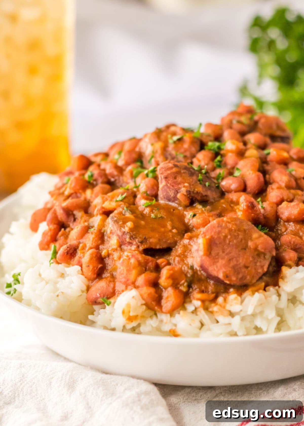 View from the side of a plate of rice topped with red beans and sausage.
