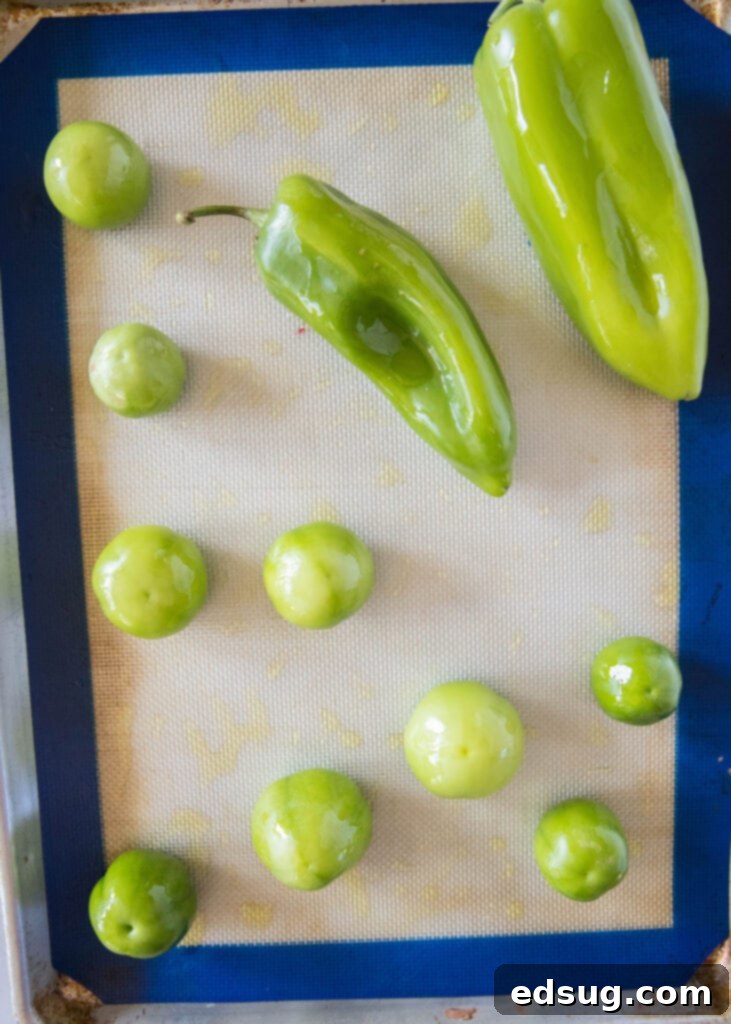 Pork Verde 5 Fresh green peppers and tomatillos ready for roasting on a baking sheet.