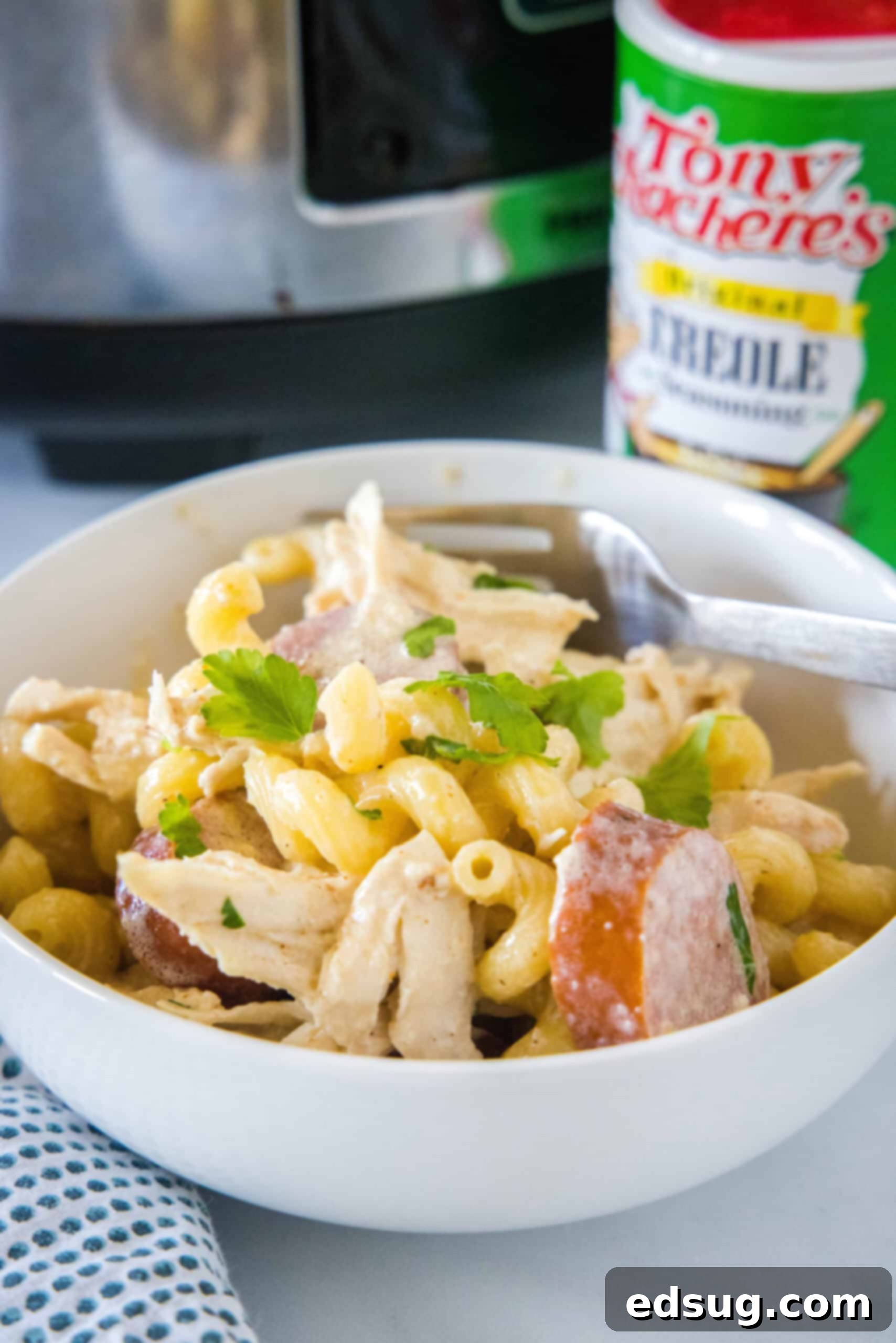 This creamy crockpot Cajun chicken pasta is easy to make in the slow cooker with spicy sausage and a rich, cheesy sauce. Just add pasta! Crockpot Cajun chicken pasta in a bowl with a fork, showing its creamy texture and rich color.