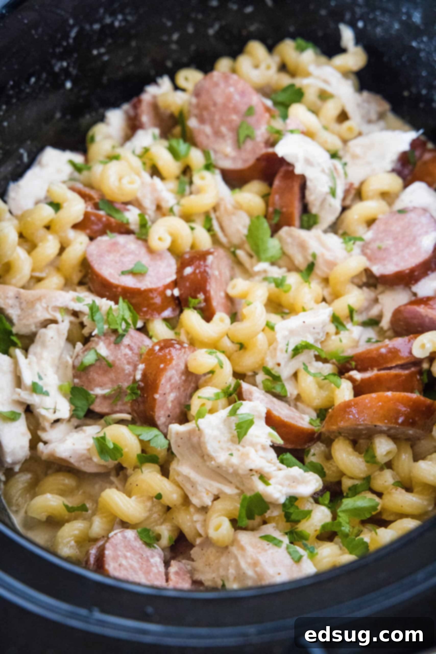 This creamy crockpot Cajun chicken pasta is easy to make in the slow cooker with spicy sausage and a rich, cheesy sauce. Just add pasta! An overhead shot of a slow cooker filled with creamy Cajun chicken pasta, ready to be served.