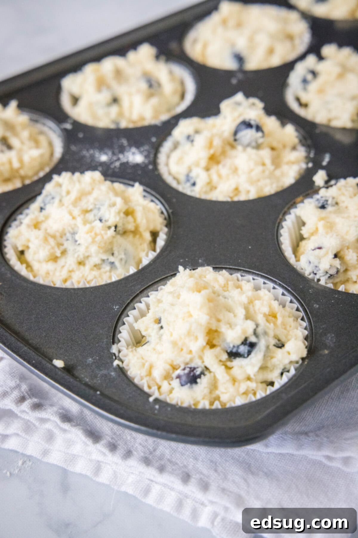 Effortless Blueberry Bliss 5 Muffin batter filled into a muffin tin, ready for baking