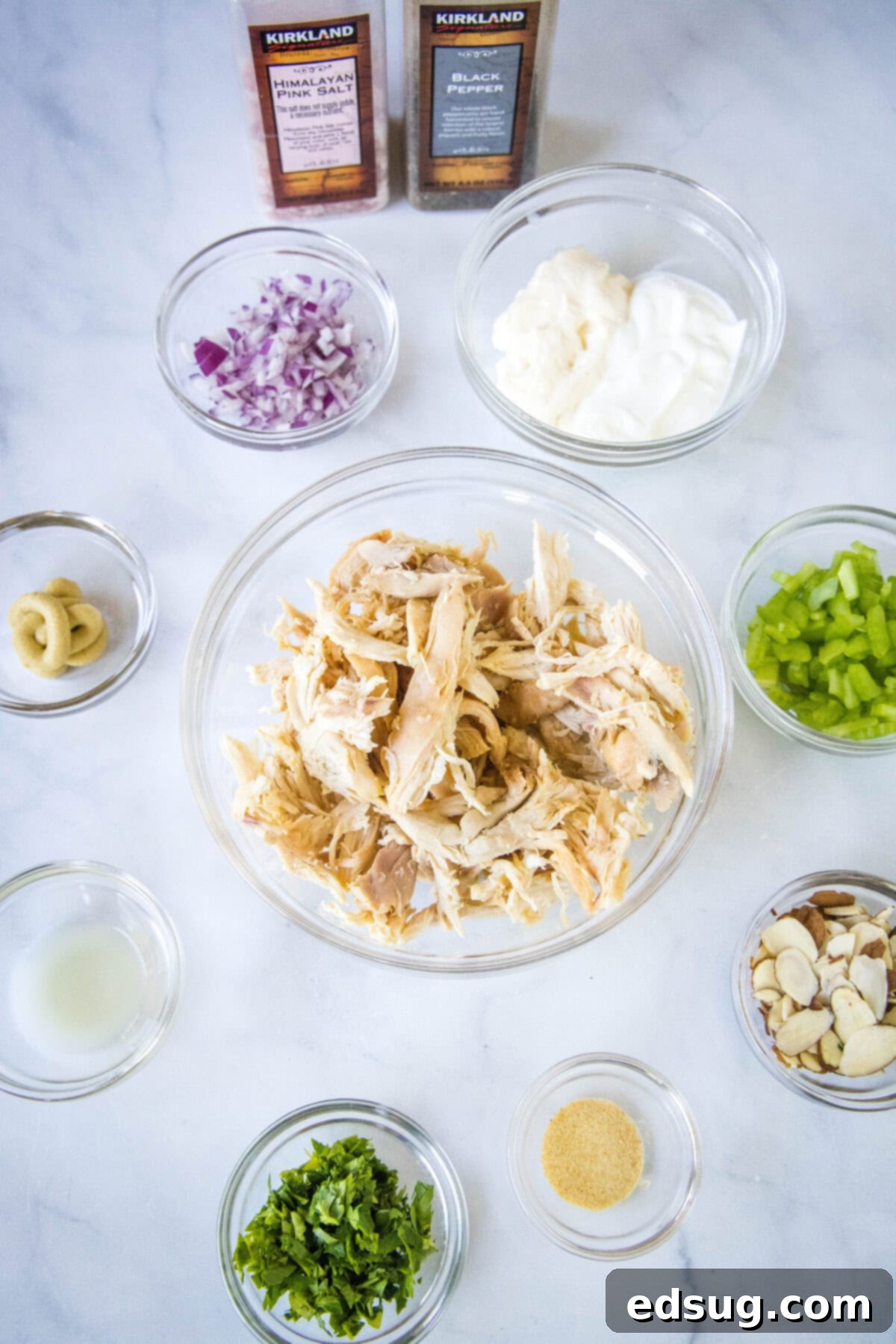 Effortless Rotisserie Chicken Salad 3 A collection of fresh ingredients laid out for making rotisserie chicken salad, including shredded chicken, celery, red onion, and parsley.