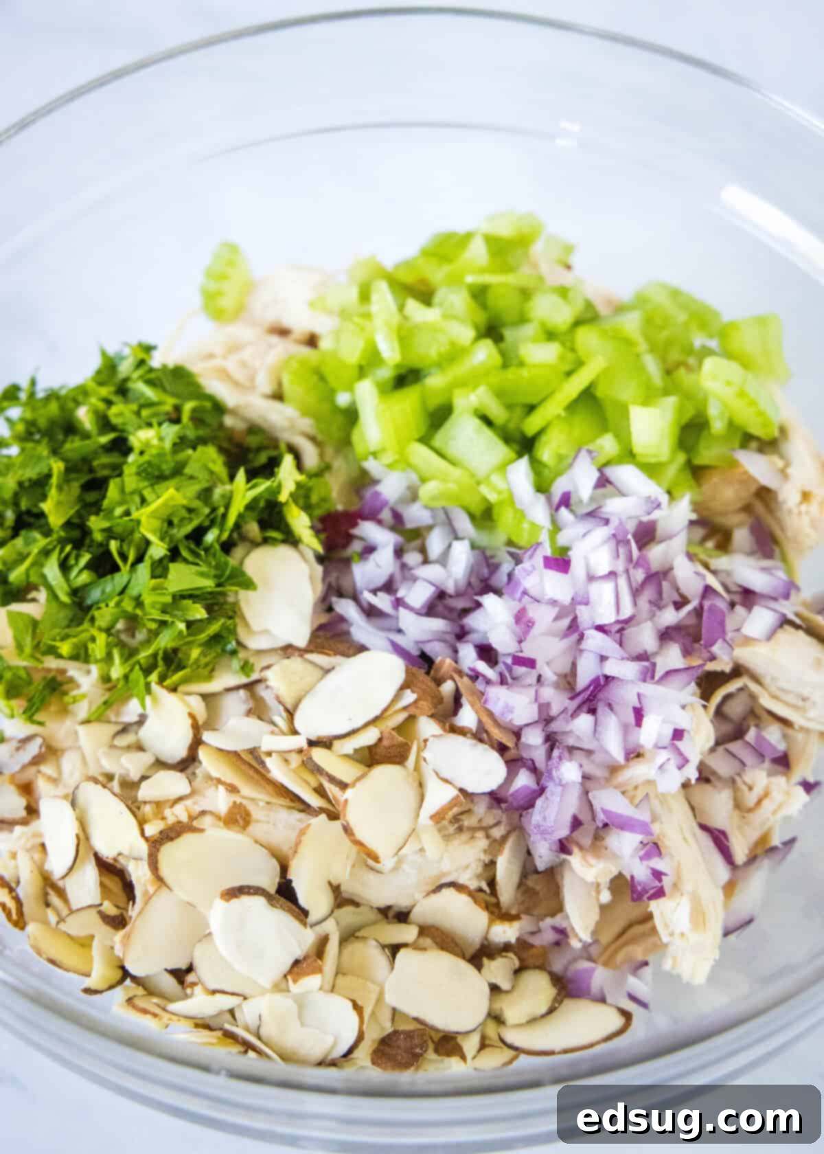 Effortless Rotisserie Chicken Salad 4 Shredded rotisserie chicken, chopped parsley, diced red onion, and celery, along with sliced almonds, in a large mixing bowl.