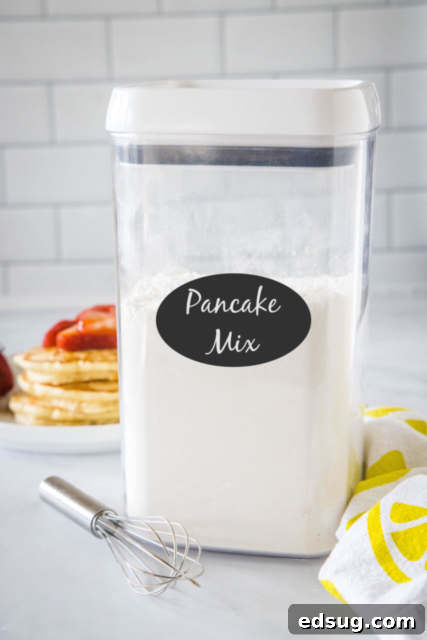 My homemade pancake mix needs only 5 ingredients! Whisk it together and keep this mix in the pantry for irresistibly fluffy pancakes anytime. A beautifully labelled airtight container brimming with homemade pancake mix, prominently displayed on a kitchen countertop, emphasizing its convenience and pantry-friendly storage.