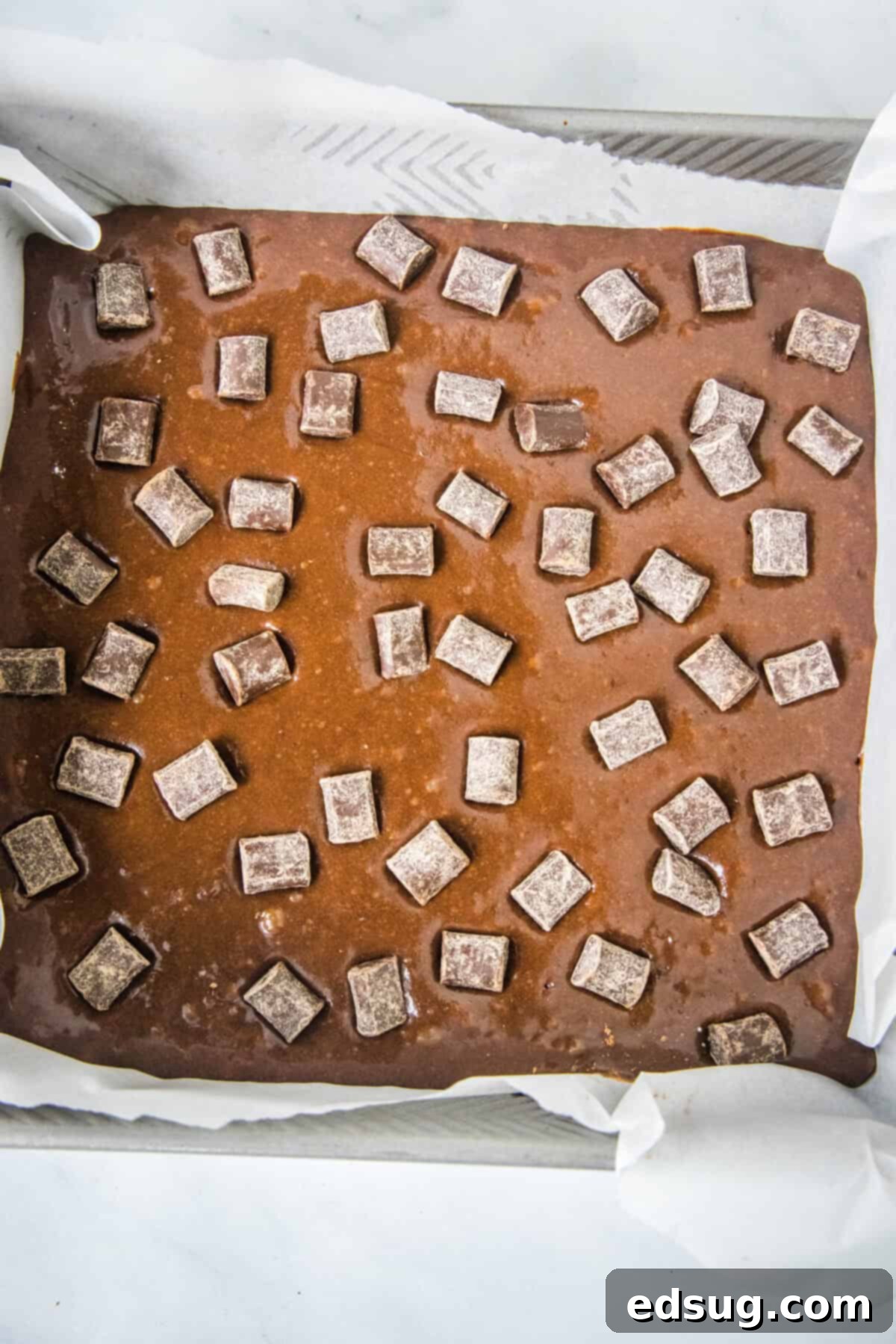 Decadent Chocolate Chunk Brownies 4 Brownie batter poured into a baking pan, topped with chocolate chunks and ready for the oven, hinting at the delicious treat to come.