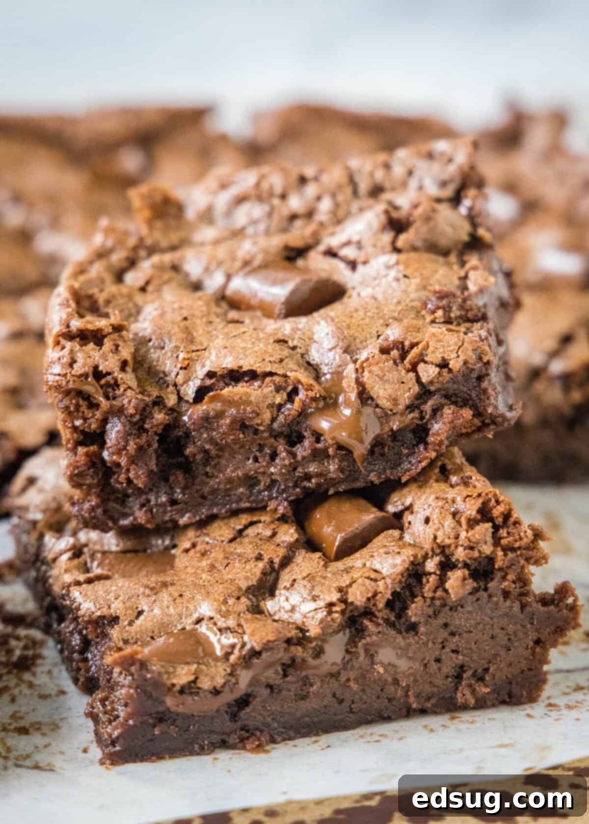 Decadent Chocolate Chunk Brownies 6 A stack of three rich, fudgy chocolate chunk brownies, showcasing their thick texture and generous chocolate chunks.