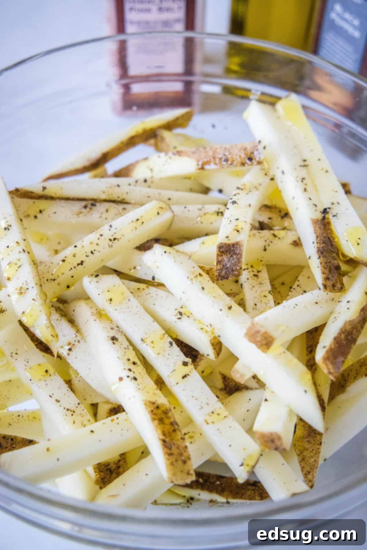 Homemade air fryer French fries are just as crispy as regular fries! Make them in a fraction of the time, with any seasonings you’d like. Cut and seasoned French fries in a bowl.