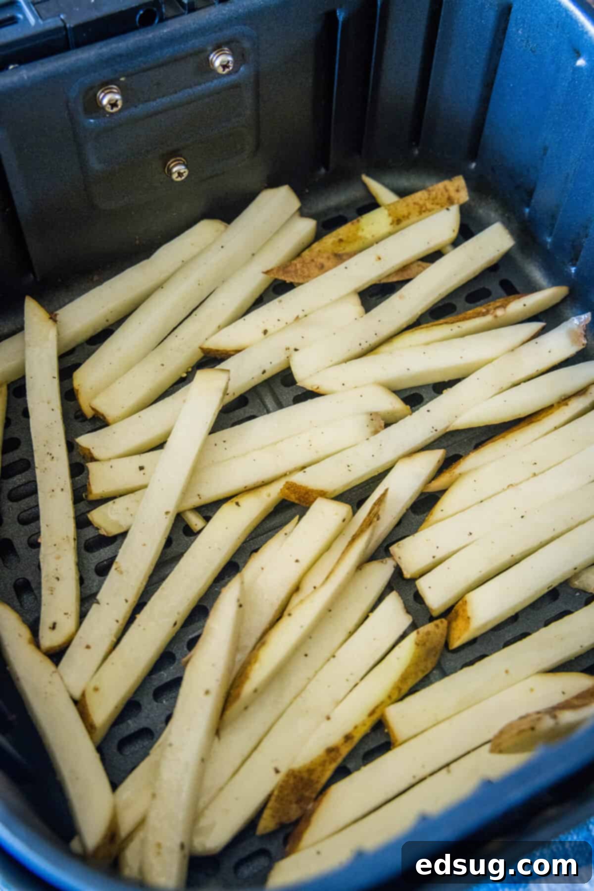 Homemade air fryer French fries are just as crispy as regular fries! Make them in a fraction of the time, with any seasonings you’d like. Uncooked homemade French fries inside the air fryer basket.