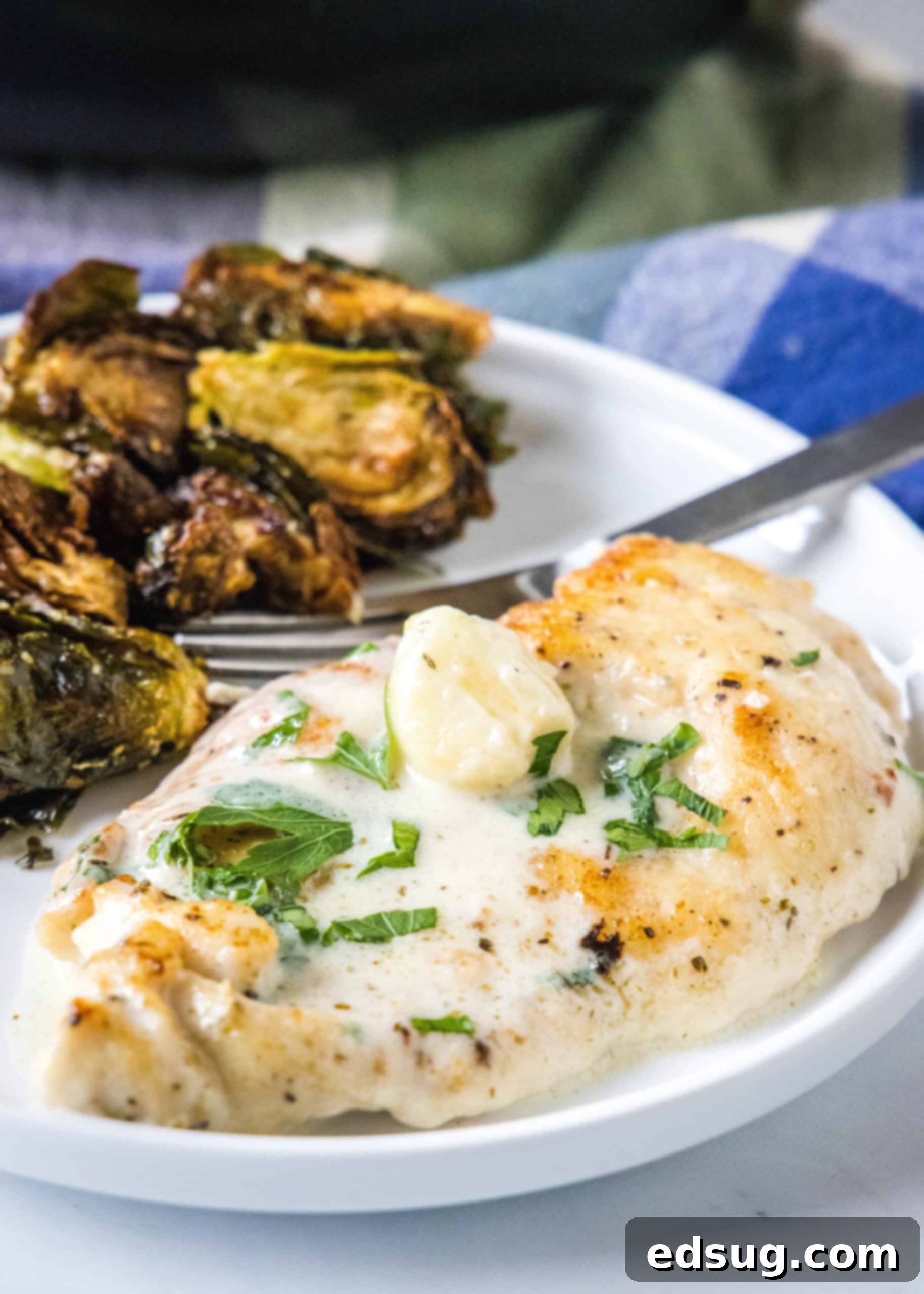 Creamy garlic chicken served with a side of roasted Brussels sprouts on a plate.