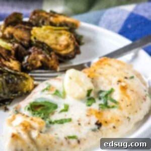 Creamy garlic chicken served with a side of roasted Brussels sprouts on a plate.