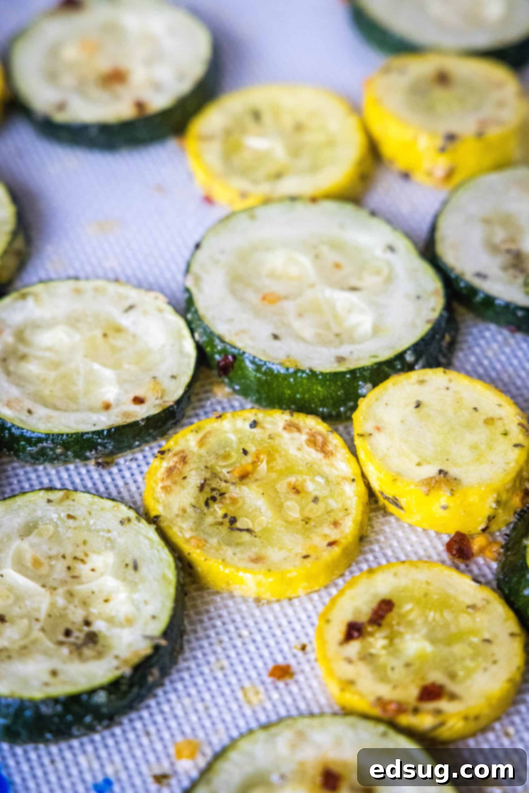 Roasted zucchini and squash slices on a lined baking sheet.