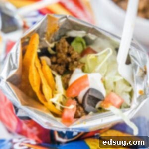 Your Handheld Taco Feast 2 A walking taco topped with lettuce, tomatoes, and sour cream inside a chip bag with a fork.