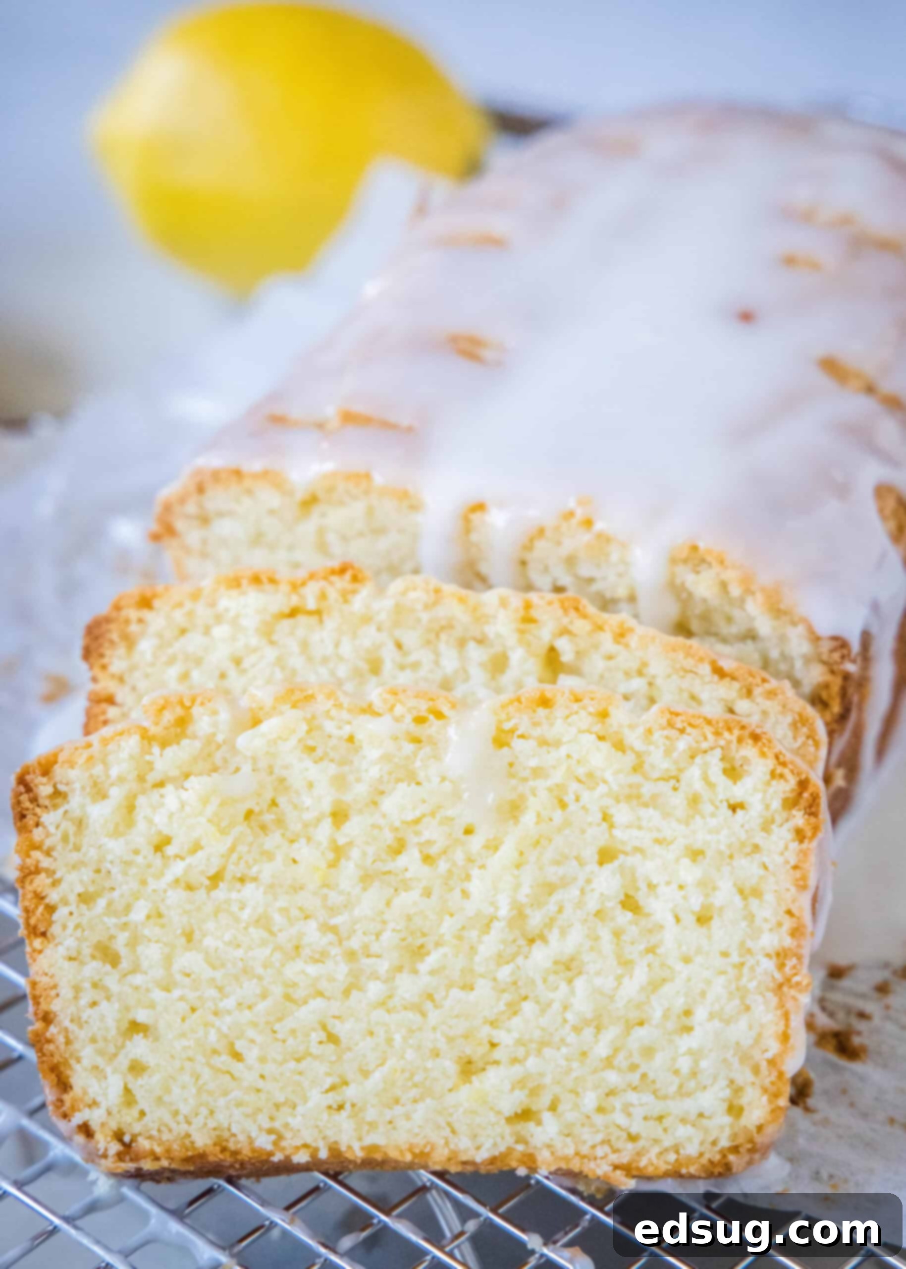 Glazed lemon loaf with two slices cut from the end, showcasing its moist texture.