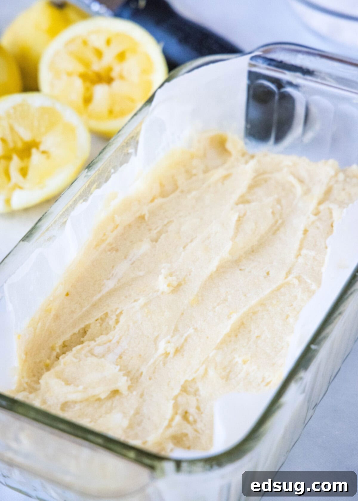Smooth lemon bread batter inside a clear glass loaf pan, ready for baking.