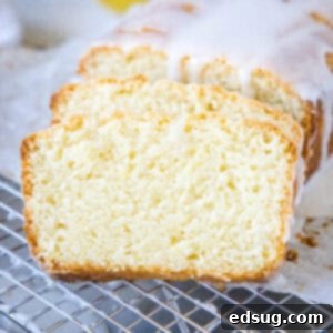 Glazed lemon loaf with two slices cut from the end on a wire rack.