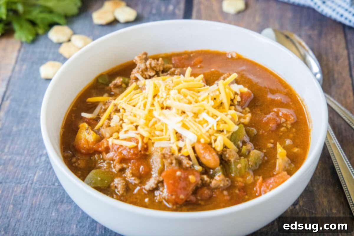 Copycat Wendy's Chili Recipe 8 A inviting bowl of Wendy's style chili, generously topped with a blanket of melted cheese, highlighting its hearty texture and inviting warmth.