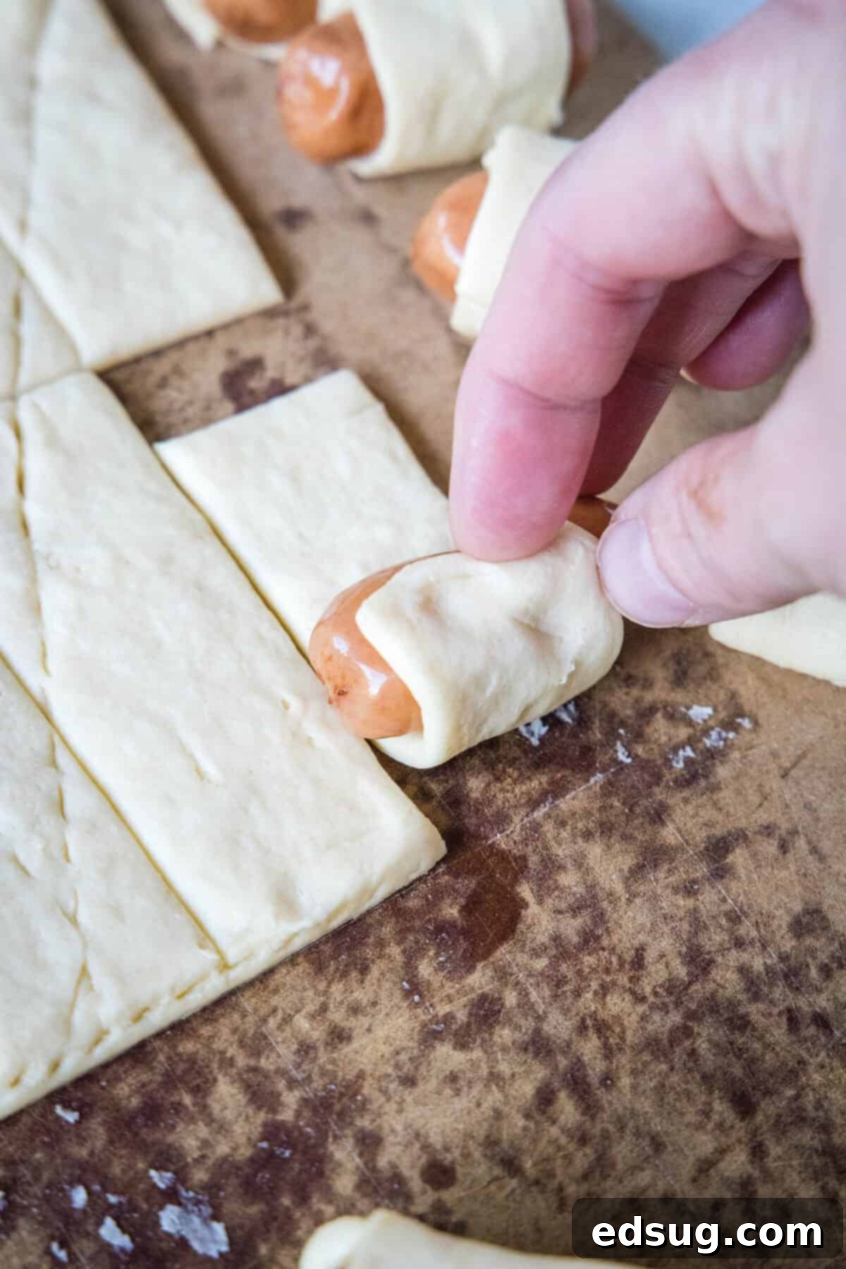 rolling a cocktail sausage in crescent dough