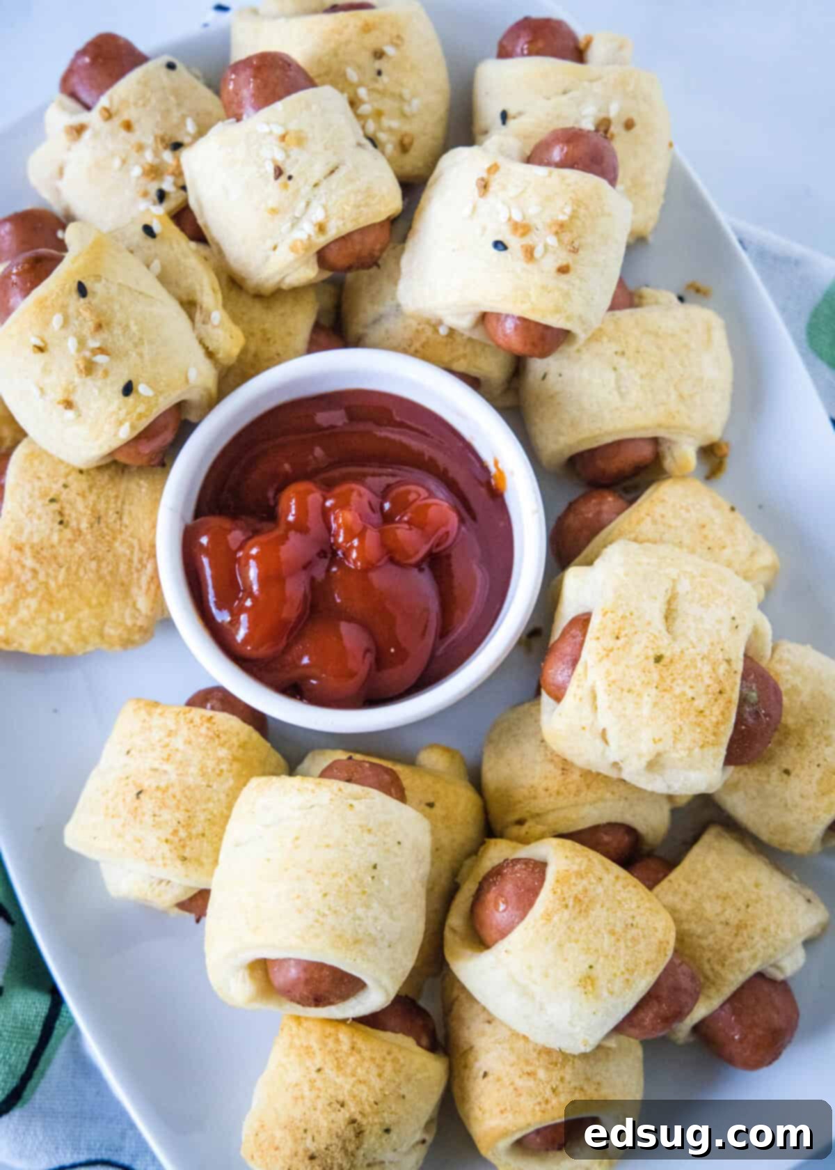 looking down on serving platter with mini pigs in a blanket with ketchup