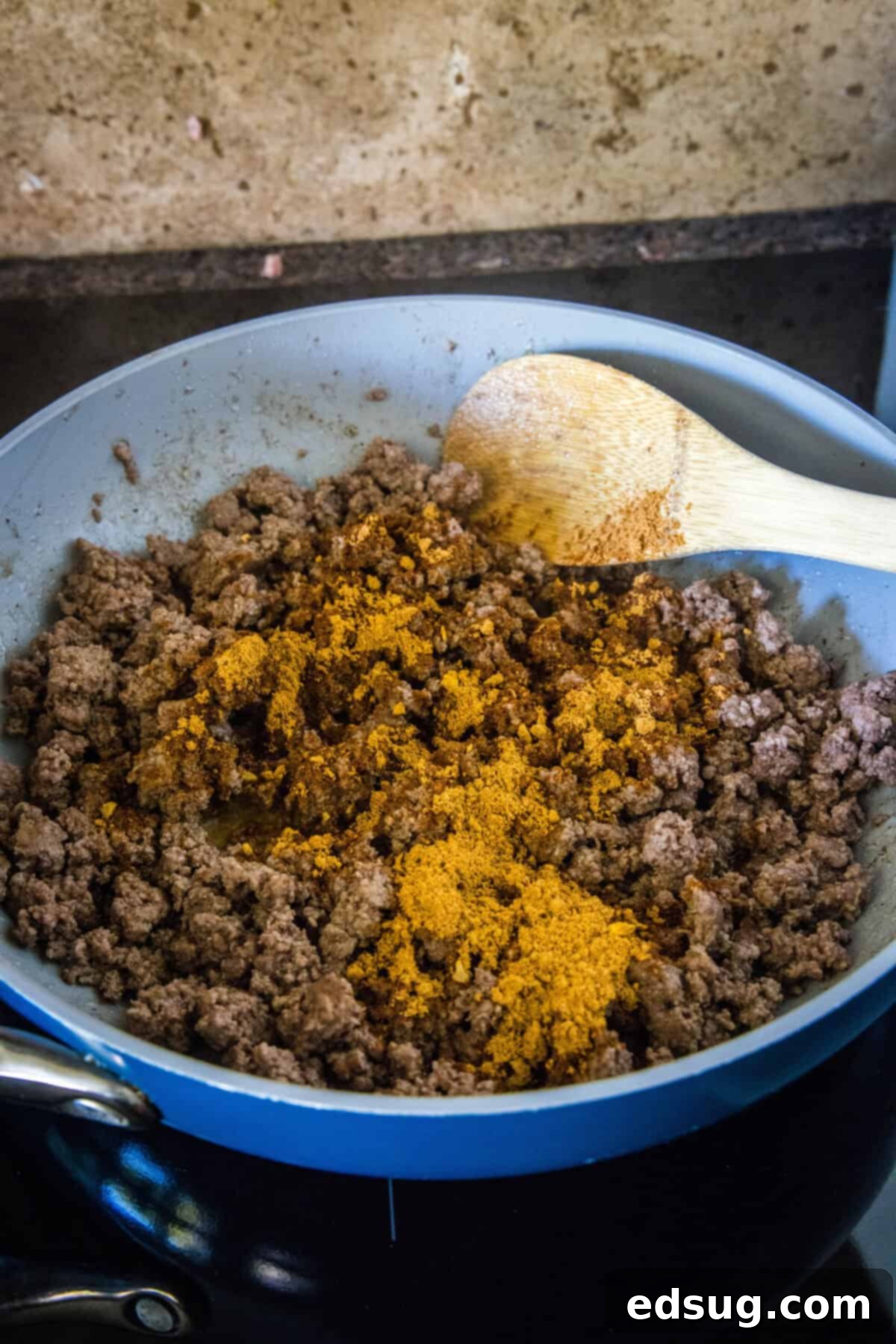 The Go-To Rotel Cheese Dip 4 adding taco seasoning to ground beef in a skillet