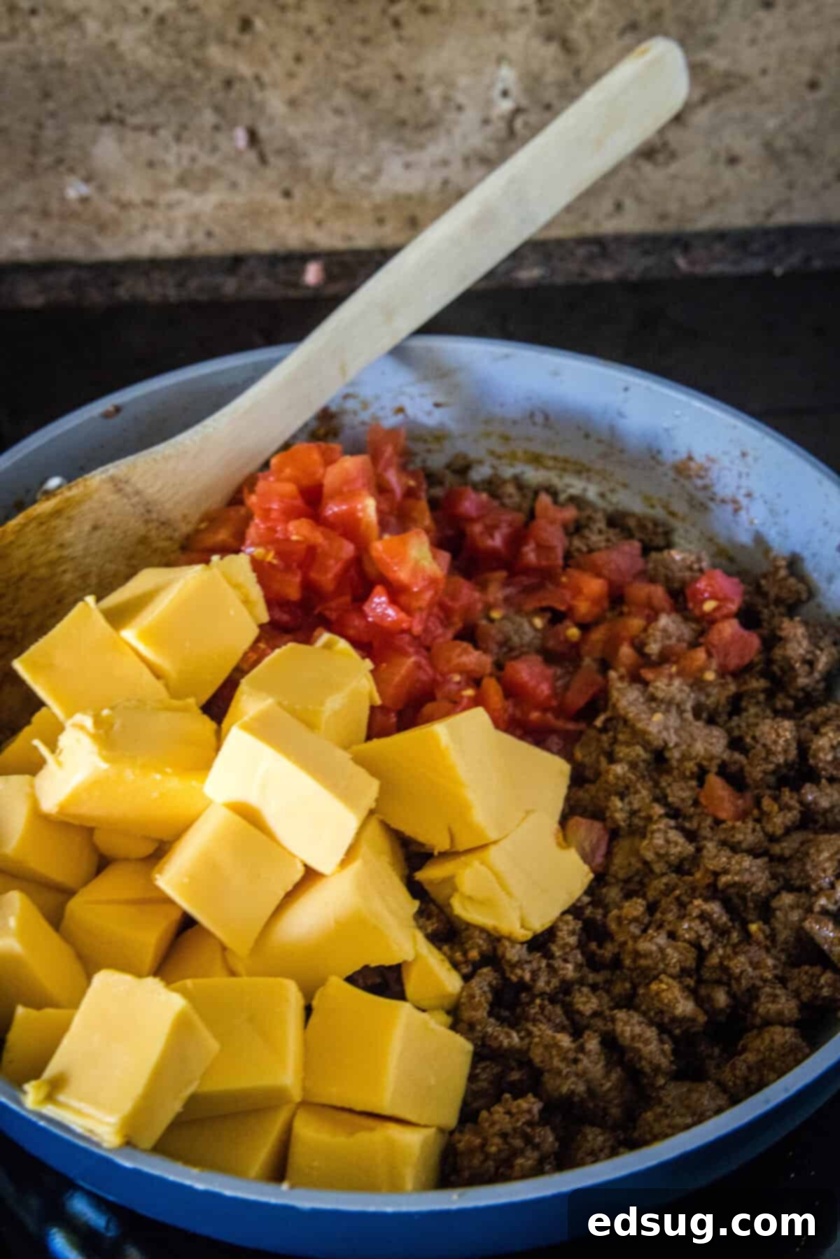 The Go-To Rotel Cheese Dip 5 adding tomatoes and velveeta to taco meat in a skillet