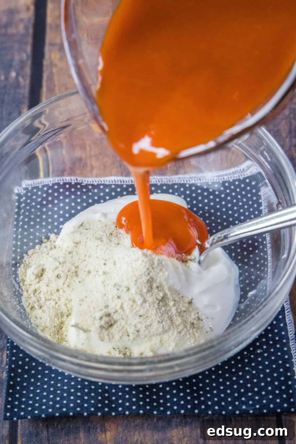 Fiery Buffalo Chicken Salad 4 buffalo sauce being poured into bowl with mayo and ranch seasoning