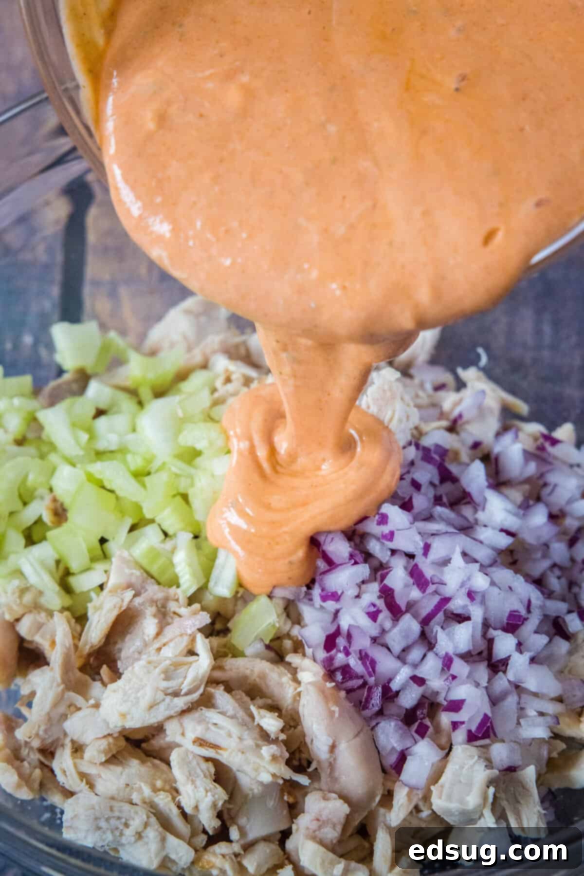 Fiery Buffalo Chicken Salad 5 pouring buffalo dressing over chicken, onions and celery