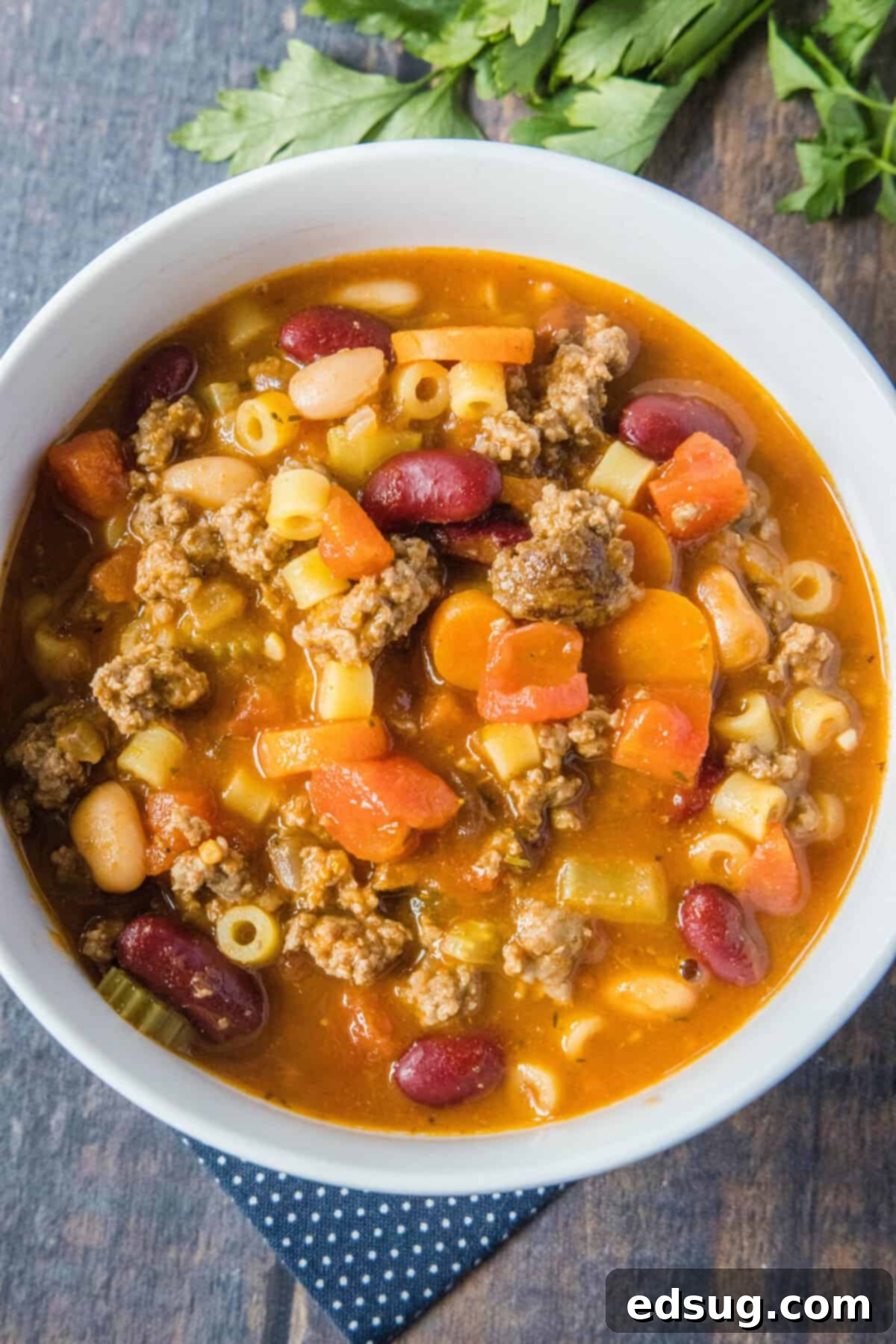 Pasta and Beans 7 Overhead shot of a rustic bowl filled with steaming Pasta e Fagioli soup, garnished with fresh herbs and a generous sprinkle of Parmesan cheese.
