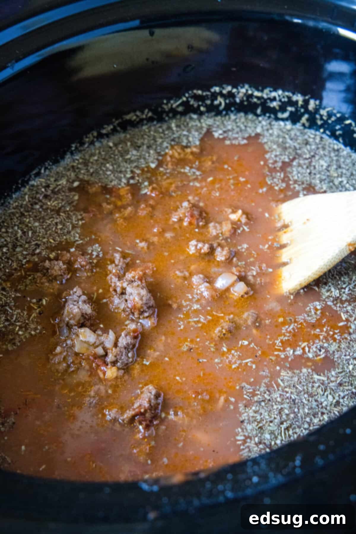 Effortless Lasagna Bowl 4 Adding browned ground beef, onions, and tomato products to a slow cooker for lasagna soup preparation