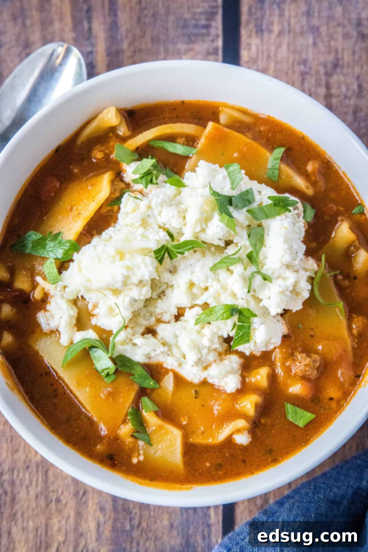 Effortless Lasagna Bowl 7 Overhead view of a hearty bowl of Slow Cooker Lasagna Soup with melted cheese, basil, and a spoon