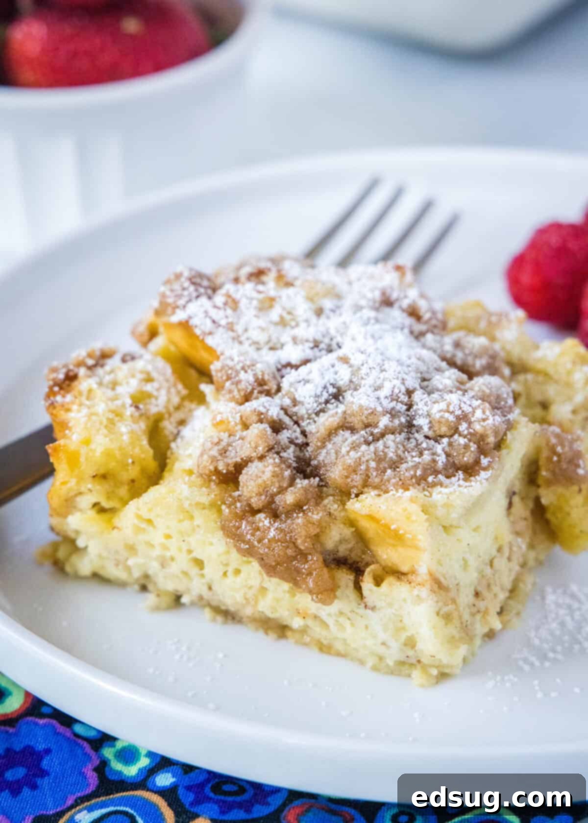 Sleep-In French Toast Casserole 8 slice of French toast casserole with powdered sugar on a white plate