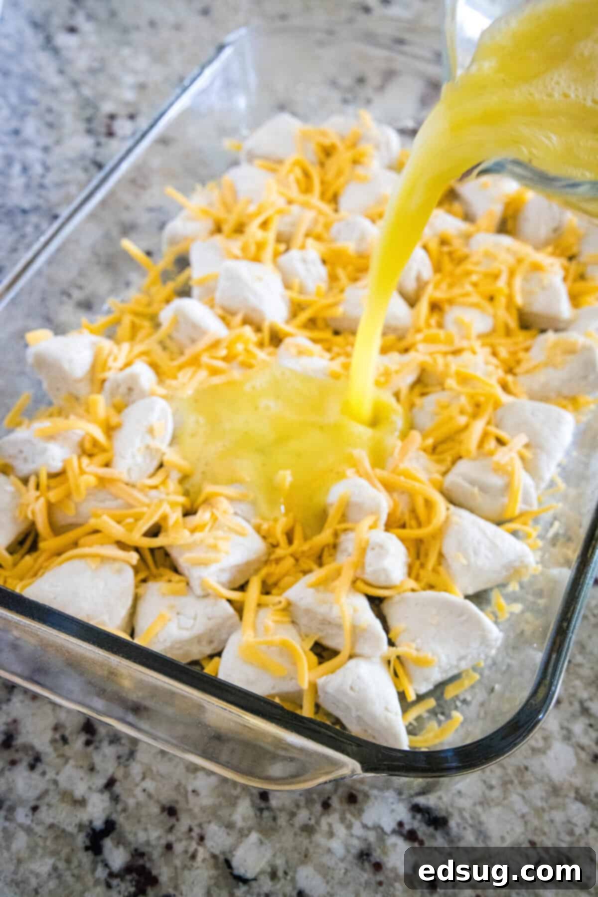 Southern Style Biscuits and Gravy Bake 4 pouring egg mixture over biscuits and cheese