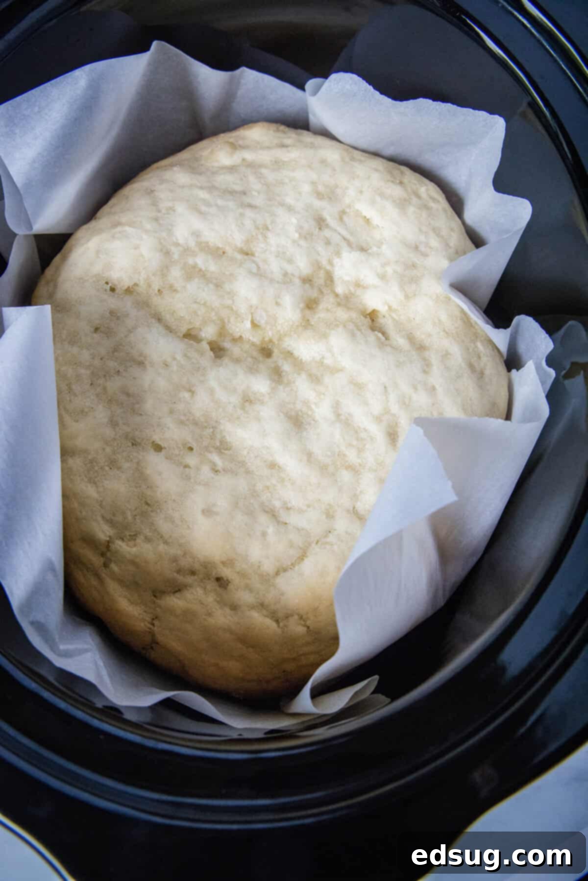 Effortless Slow Cooker Bread 7 A freshly baked loaf of slow cooker bread, light golden on the sides and pale on top, resting inside the crockpot after cooking.