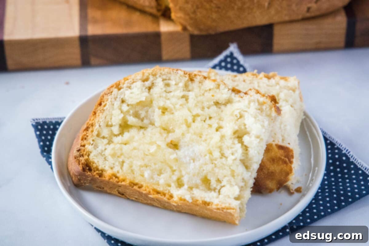Effortless Slow Cooker Bread 10 An overhead view of a golden-brown slow cooker bread loaf, sliced and buttered, on a light plate with a fork. It emphasizes the soft, fluffy texture.
