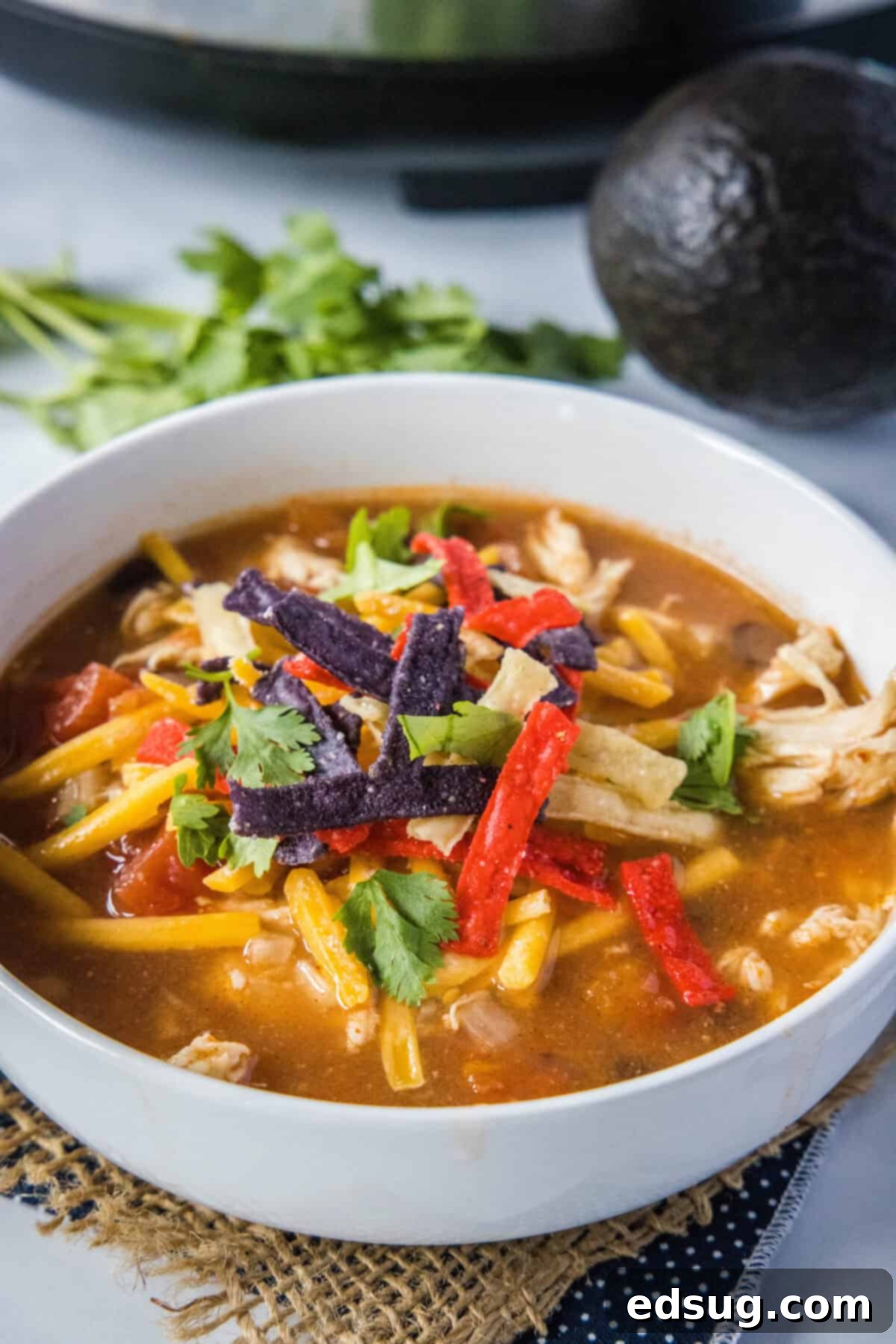 A comforting bowl of Crockpot Chicken Tortilla Soup with fresh toppings like avocado, cheese, and crispy tortilla strips.