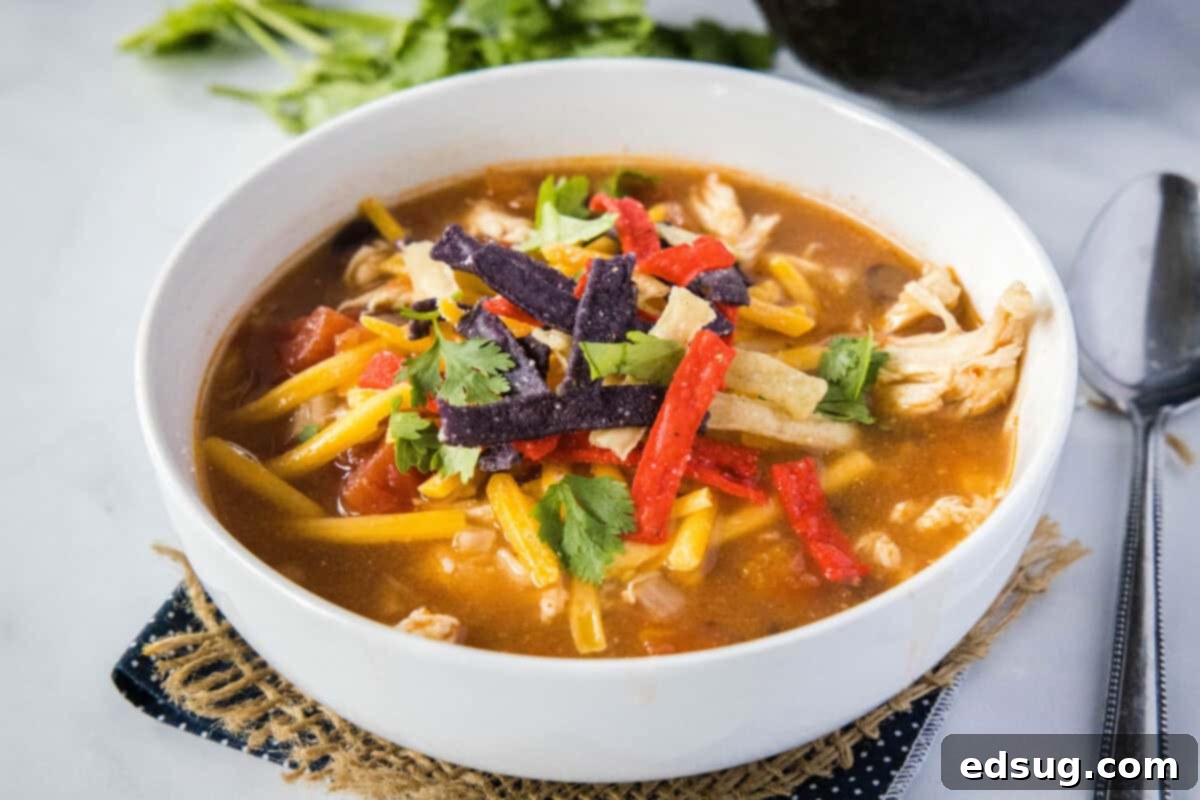 A beautifully arranged bowl of Crockpot Chicken Tortilla Soup with a full spread of topping options, ready to customize.