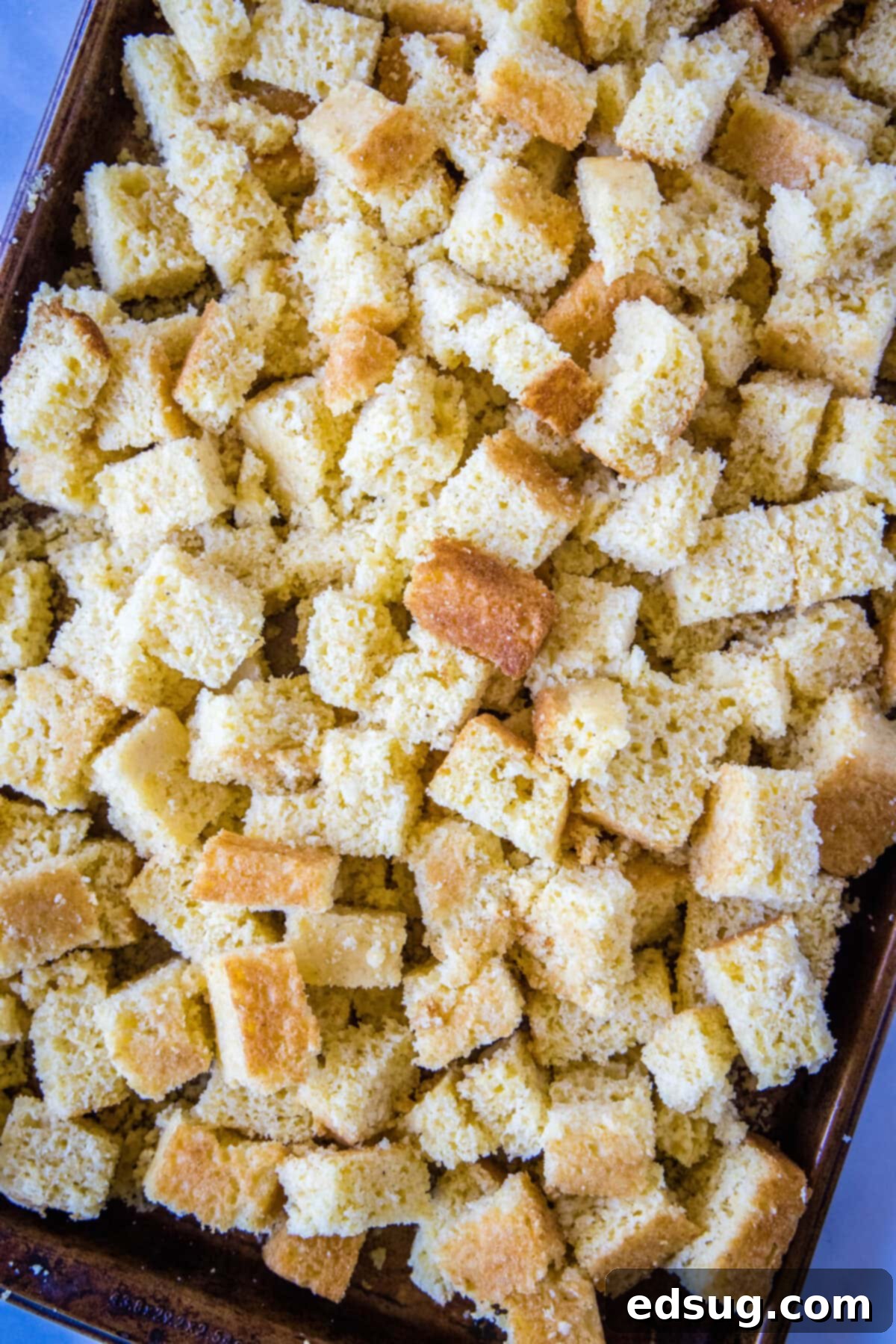 Easy cornbread stuffing is packed with meaty sausage, herbaceous seasonings, and a hearty cornbread, and is the perfect holiday side dish. Overhead view of a tray of cornbread chunks