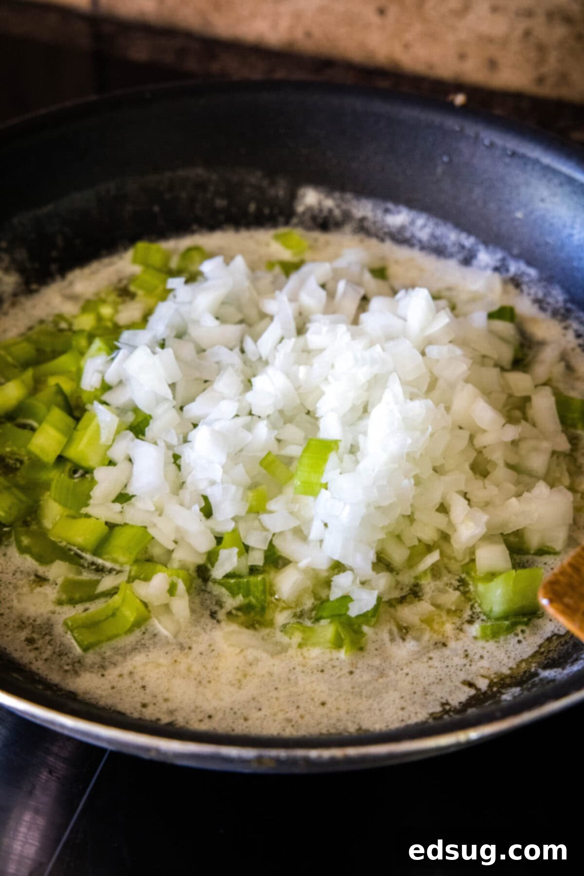 Easy cornbread stuffing is packed with meaty sausage, herbaceous seasonings, and a hearty cornbread, and is the perfect holiday side dish. Onions and celery in a skillet with butter