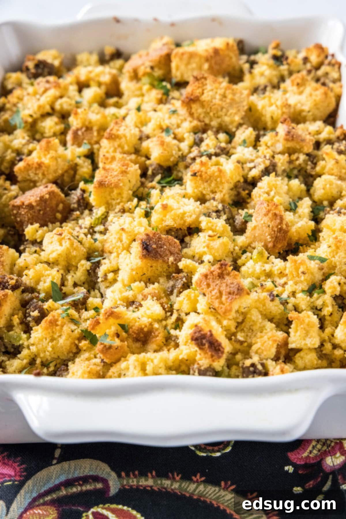 Easy cornbread stuffing is packed with meaty sausage, herbaceous seasonings, and a hearty cornbread, and is the perfect holiday side dish. Close up of a casserole dish full of cornbread stuffing