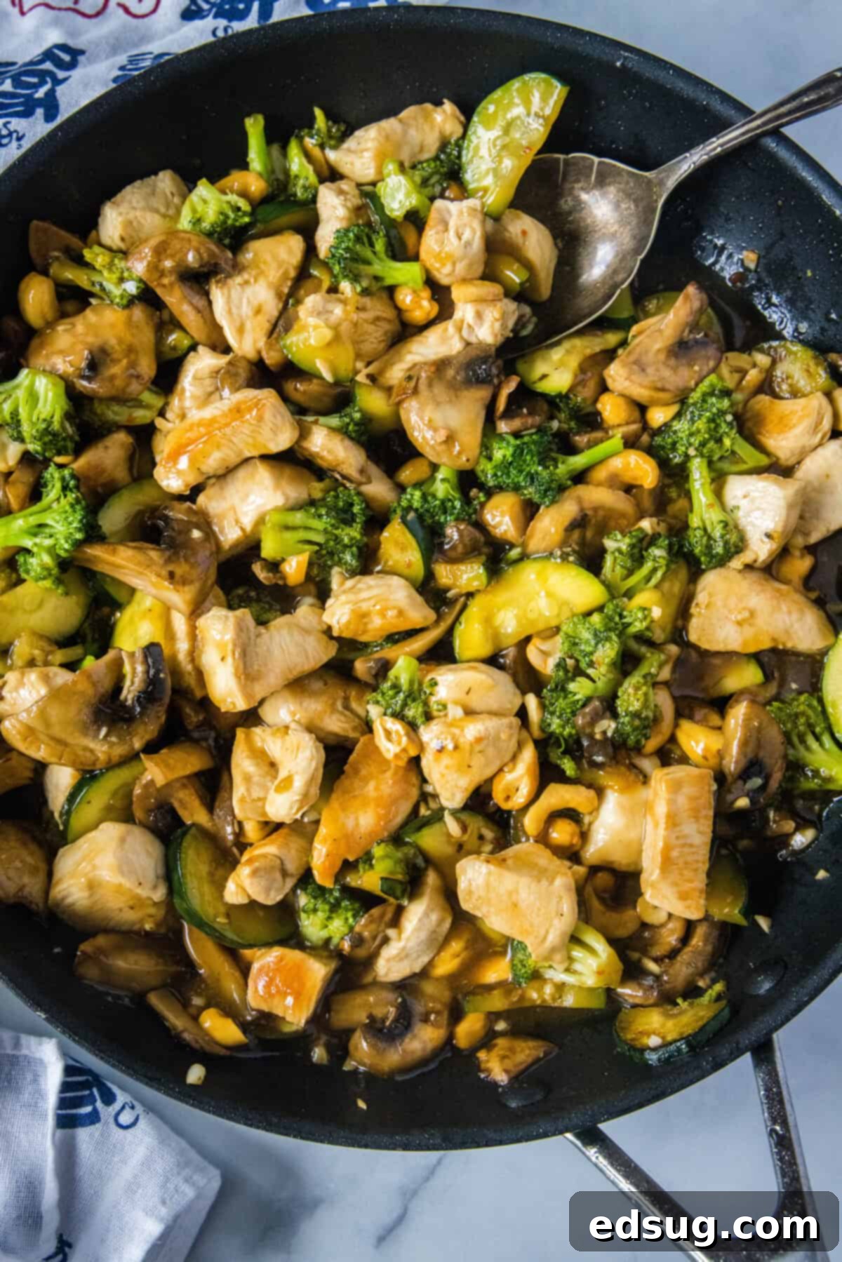 looking down on skillet with finished chicken stir fry, ready to be served, showing the golden chicken and colorful vegetables