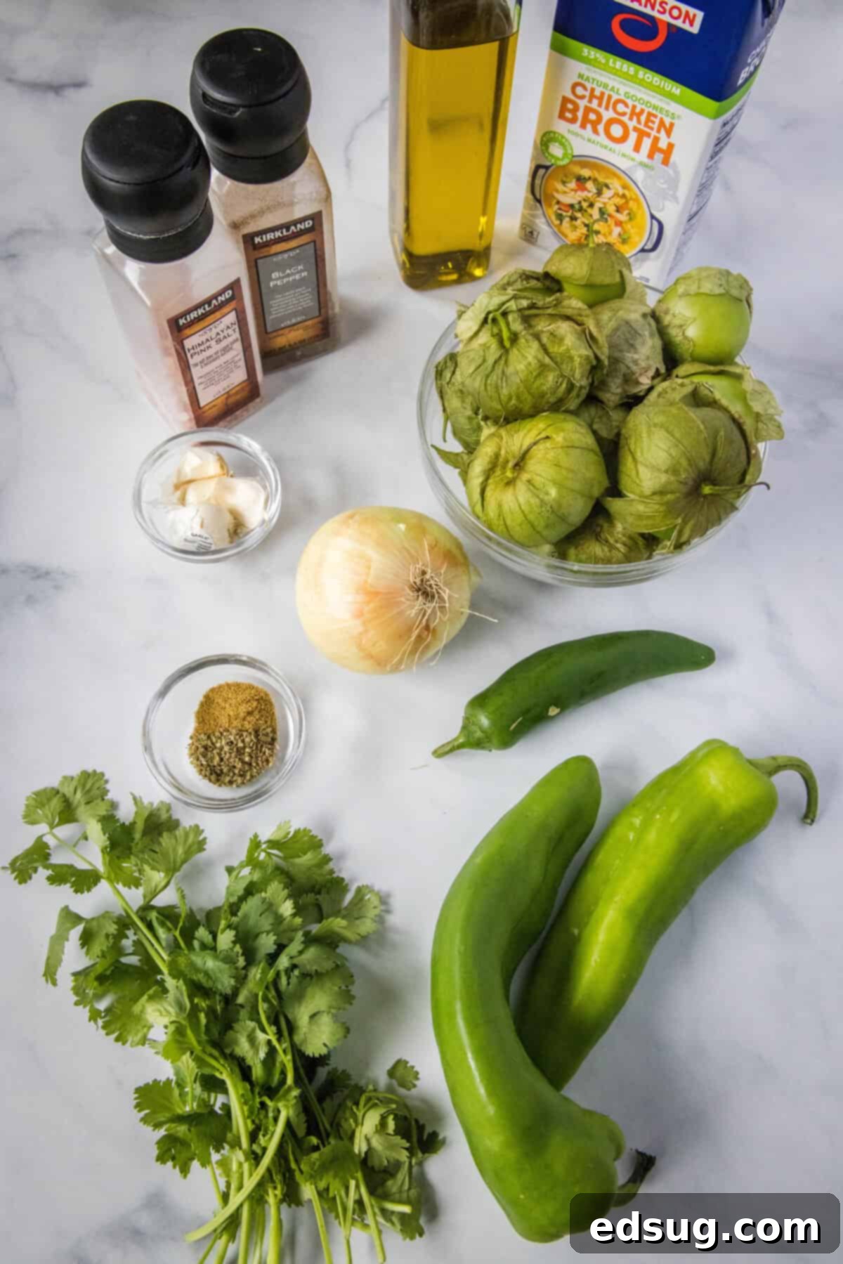 Authentic Green Enchilada Sauce 3 Fresh ingredients laid out on a wooden cutting board, including vibrant green tomatillos, various green peppers, an onion, garlic cloves, and fresh cilantro, ready for making green enchilada sauce.