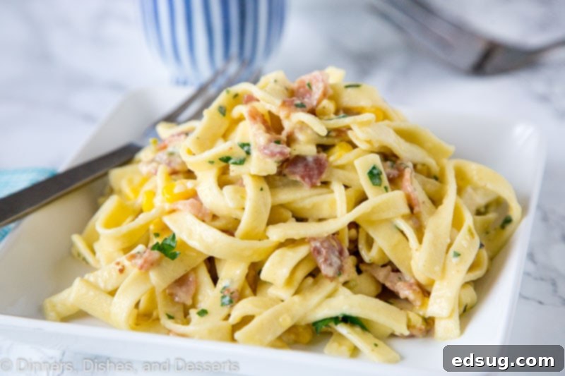 Fiesta Carbonara 5 A wide shot of pasta carbonara with corn and chilies served on a large plate with a fork, ready to be enjoyed as a meal