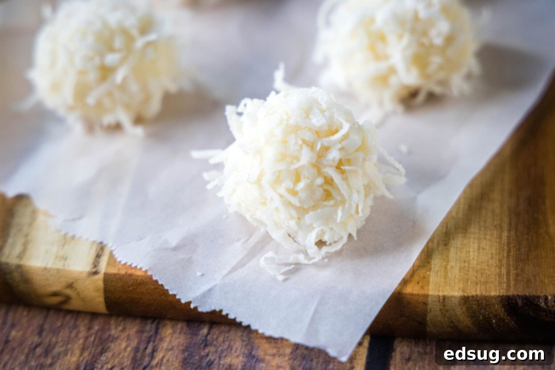 Close up of perfectly formed white chocolate truffles with coconut on a piece of parchment paper, ready to be enjoyed