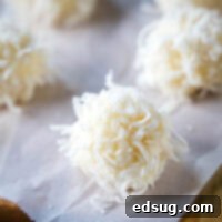 Close up of a white chocolate truffle topped with coconut next to others