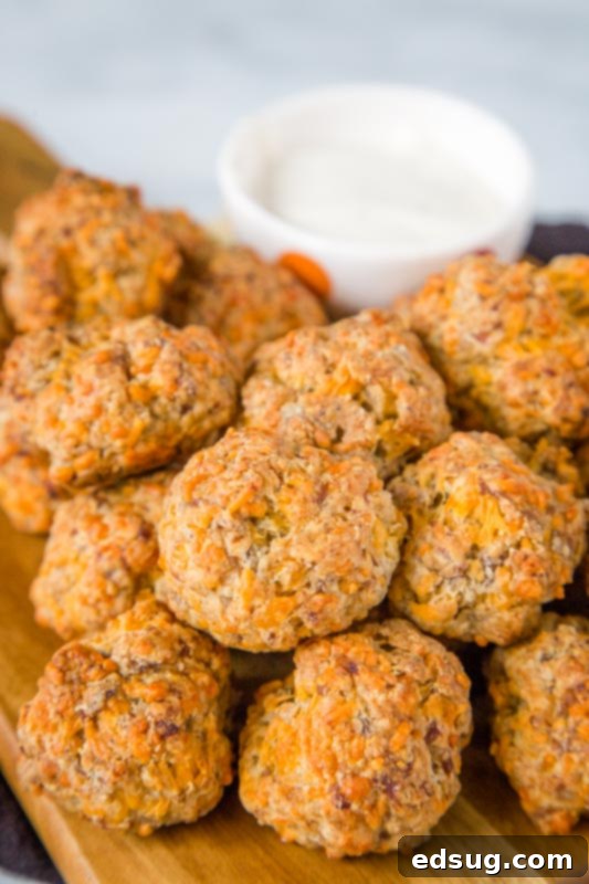 Golden brown cheesy sausage balls on a white plate with a festive napkin, ready to be served as an appetizer.