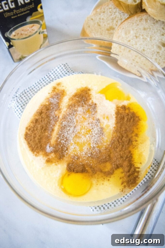 A bowl of creamy eggnog and egg mixture, perfectly spiced with cinnamon and nutmeg, ready for dipping thick slices of bread to make delicious French toast.